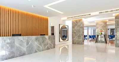 a lobby with a reception desk and a mirror at Blue Sea Holiday Village in Afantou