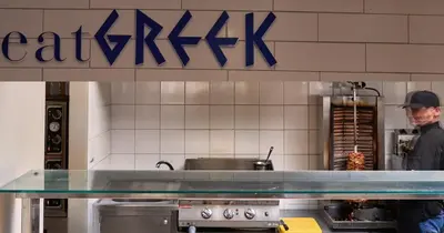 a man standing behind a counter in a kitchen at Blue Sea Holiday Village in Afantou