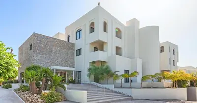 a white building with palm trees in front of it at Blue Sea Holiday Village in Afantou