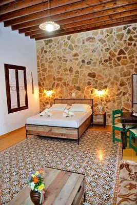 a bedroom with a bed and a stone wall at Meandros Suite in Old Town in Rhodes Town