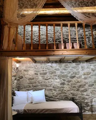 a bed in a room with a stone wall at M&M STONE-Village House-Family-Vintage in Líndos