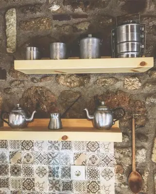 a shelf with pots and pans on a wall at M&M STONE-Village House-Family-Vintage in Líndos