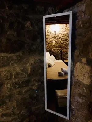 a mirror reflection of a bedroom in a stone wall at M&M STONE-Village House-Family-Vintage in Líndos