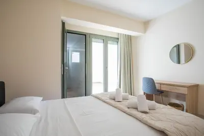 a bedroom with a large white bed with a chair at Eden Lily- Luxurious Apartment with Sea View in Rhodes Town
