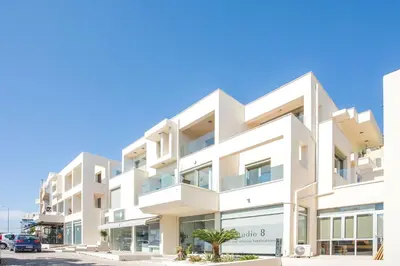 a white building with a palm tree in front of it at Eden Lily- Luxurious Apartment with Sea View in Rhodes Town