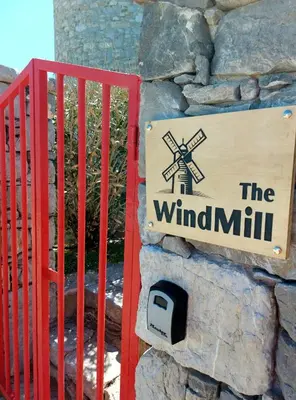 a sign for the windmill on a stone wall at The WindMill in Skala