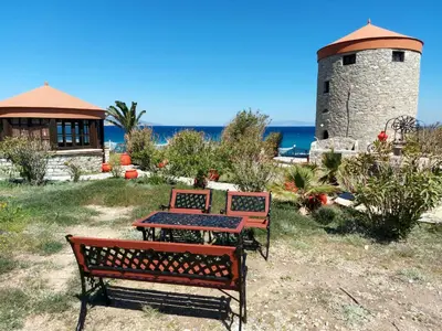 two benches and a table in front of a lighthouse at The WindMill in Skala