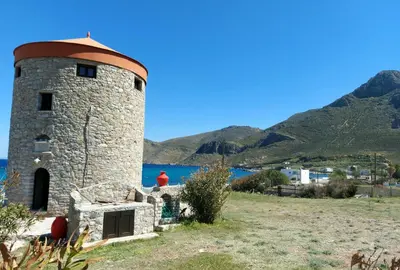a stone tower with the ocean in the background at The WindMill in Skala