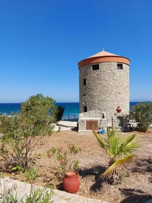 a stone lighthouse with the ocean in the background at The WindMill in Skala