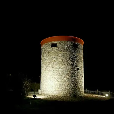 a tower with a cat sitting in front of it at night at The WindMill in Skala