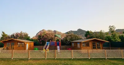 a playground with two cottages behind a fence at Blue Sea Island in Kolimbia