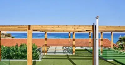 a wooden pavilion with the ocean in the background at Blue Sea Island in Kolimbia