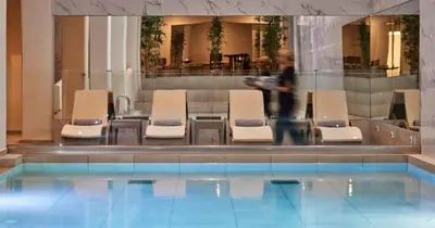 a man walking by a pool with chairs and a table at Blue Sea Island in Kolimbia