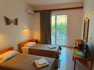 a room with two beds and a television and a window at Chrysa Apartments in Kolimbia