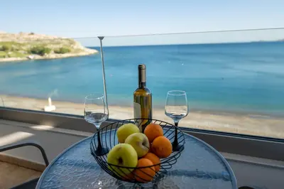 a glass table with a bowl of fruit and two wine glasses at Haraki Elegant View in Haraki