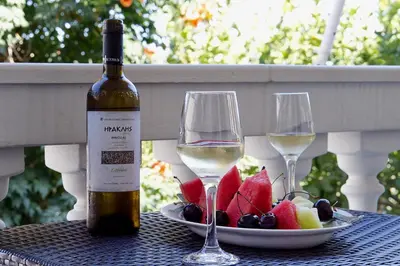 a bottle of wine and two glasses on a table with fruit at Maisonnete Lilian in Rhodes Town
