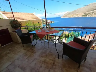 a balcony with a table and chairs and a view of the water at Villa Astradeni Symi in Symi