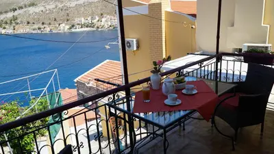 a balcony with a table and a view of the water at Villa Astradeni Symi in Symi
