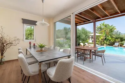 a dining room with a table and chairs and a pool at Villa Olvia in Gennadi