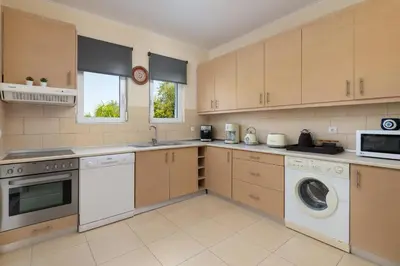 a kitchen with wooden cabinets and a washer and dryer at Villa Olvia in Gennadi