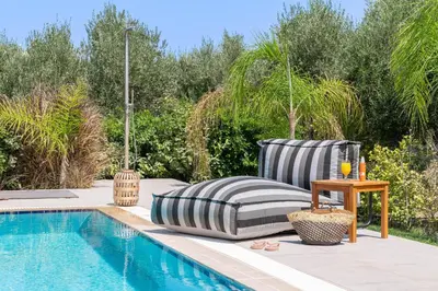 a chair and a table next to a swimming pool at Villa Olvia in Gennadi