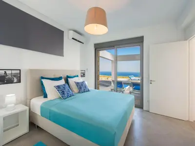 a bedroom with a blue bed with a view of the ocean at Villa in Rhodes with Infinity Pool in Kalithies
