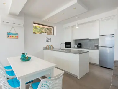 a kitchen with white cabinets and a table and chairs at Villa in Rhodes with Infinity Pool in Kalithies