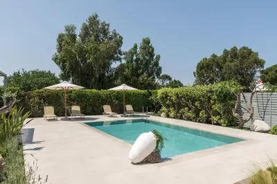a swimming pool with chairs and umbrellas at Palamoutaki Villa in Koskinou