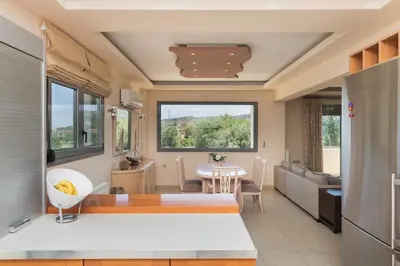 a kitchen and living room with a table and chairs at Palamoutaki Villa in Koskinou
