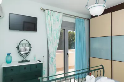a bedroom with a bed with blue curtains and a mirror at Palamoutaki Villa in Koskinou