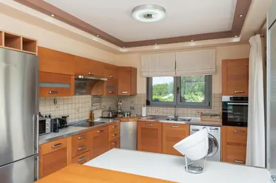 a kitchen with wooden cabinets and stainless steel appliances at Palamoutaki Villa in Koskinou