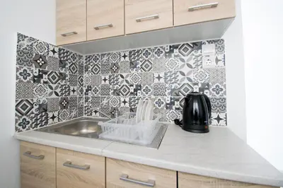 a kitchen with a sink and a tile wall at CHAMBRE JAUNE in Ialyssos