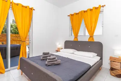 a bedroom with a bed with orange curtains at Marvinas seaside apartments, GAIA apartment & HYDOR jacuzzi apartment in Kremasti