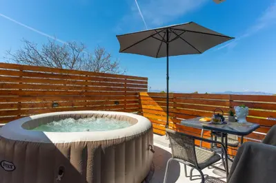 a hot tub with an umbrella on a patio at Marvinas seaside apartments, GAIA apartment & HYDOR jacuzzi apartment in Kremasti