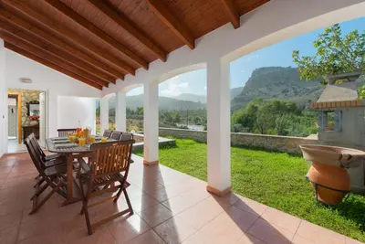 a dining room with a table and chairs on a patio at Villa Krokali Lindos in Líndos