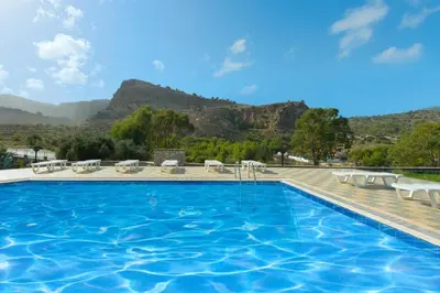 a swimming pool with chairs and a mountain in the background at Villa Krokali Lindos in Líndos