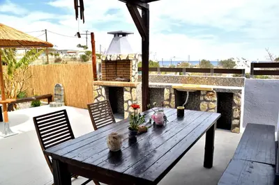 a wooden table on a patio with a fireplace at PLUMERIA HOUSE in Archangelos