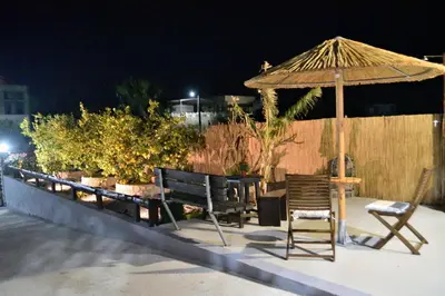 a patio with a table and an umbrella and chairs at PLUMERIA HOUSE in Archangelos