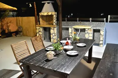 a wooden table with plates and dishes on a patio at PLUMERIA HOUSE in Archangelos