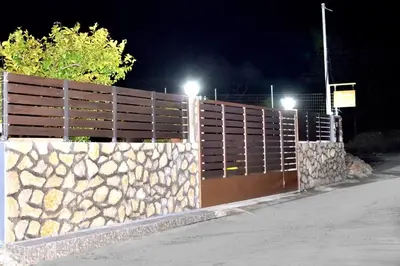 a wooden fence with a stone wall at night at PLUMERIA HOUSE in Archangelos