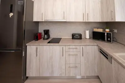 a kitchen with wooden cabinets and a stainless steel refrigerator at Searock Stegna Villa in Archangelos
