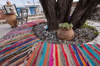 a colorful rug next to a tree with a plant at Searock Stegna Villa in Archangelos