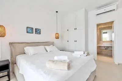a white bedroom with a large bed with towels on it at Villa Lara AmberBlue Pefkos in Pefki Rhodes