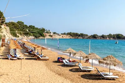 a beach with chairs and umbrellas and the ocean at Villa Lara AmberBlue Pefkos in Pefki Rhodes
