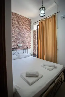 a bedroom with a large white bed with a brick wall at Star Sianna Village Rooms to let in Siána