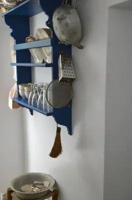 a blue shelf with dishes and a broom on a wall at Spitaki - House with Garden by the Beach - Pefki in Pefki Rhodes