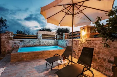 a swimming pool with two chairs and an umbrella at Villa Gemma in Haraki