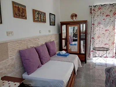a bedroom with a bed with purple pillows and a mirror at Athinas Art House in Kolimbia