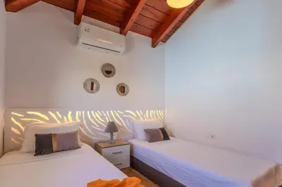 two beds in a room with white walls and wooden ceilings at Villa Christalia in Kolimbia