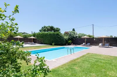 a swimming pool in a yard with grass at Marane Deluxe House in Ialyssos